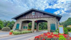 Pórtico de entrada de Gramado com canteiro de flores vermelhas em dia de sol