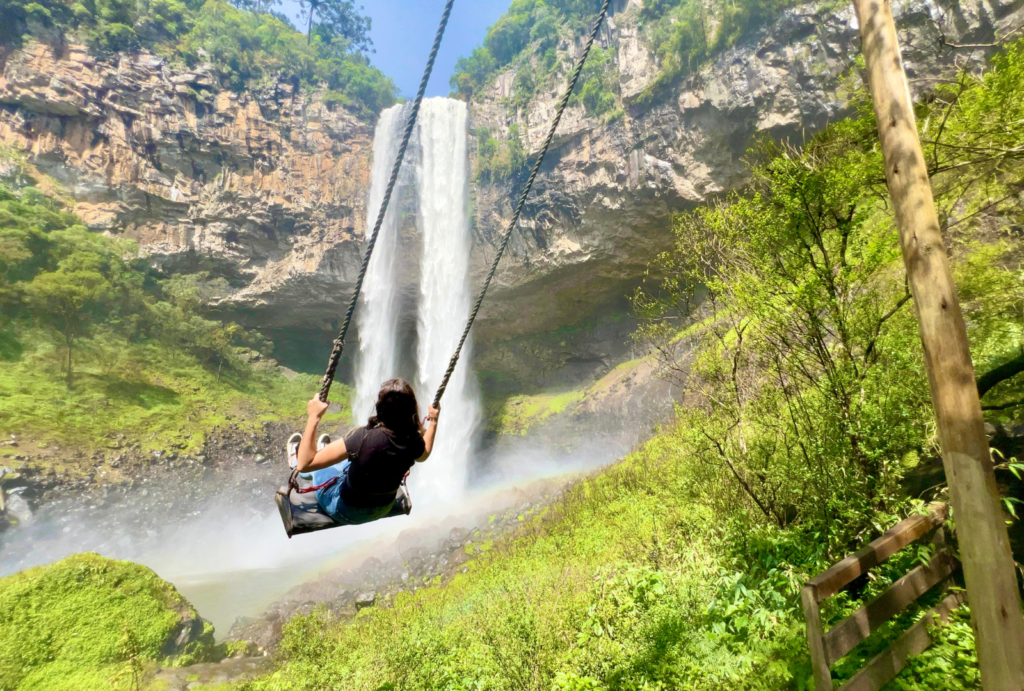 Visitante em balanço suspenso em frente à Cascata do Caracol em Canela